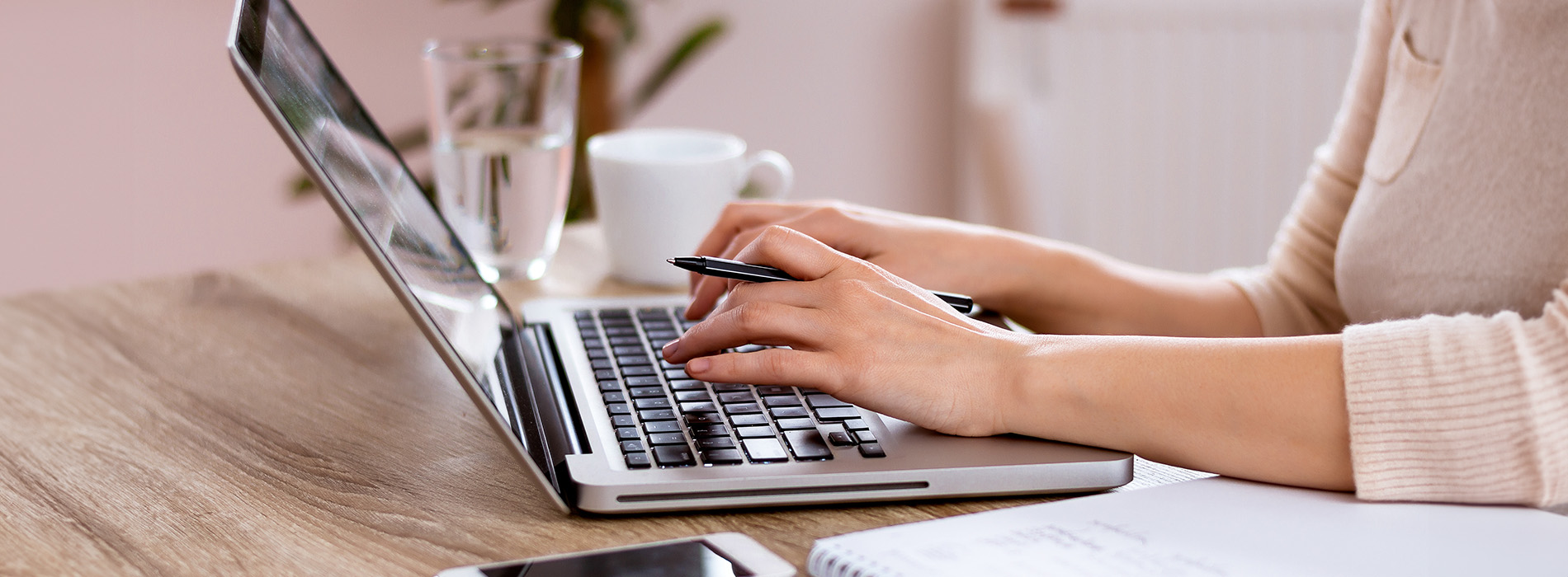 A person working at a desk with a laptop, surrounded by office items.