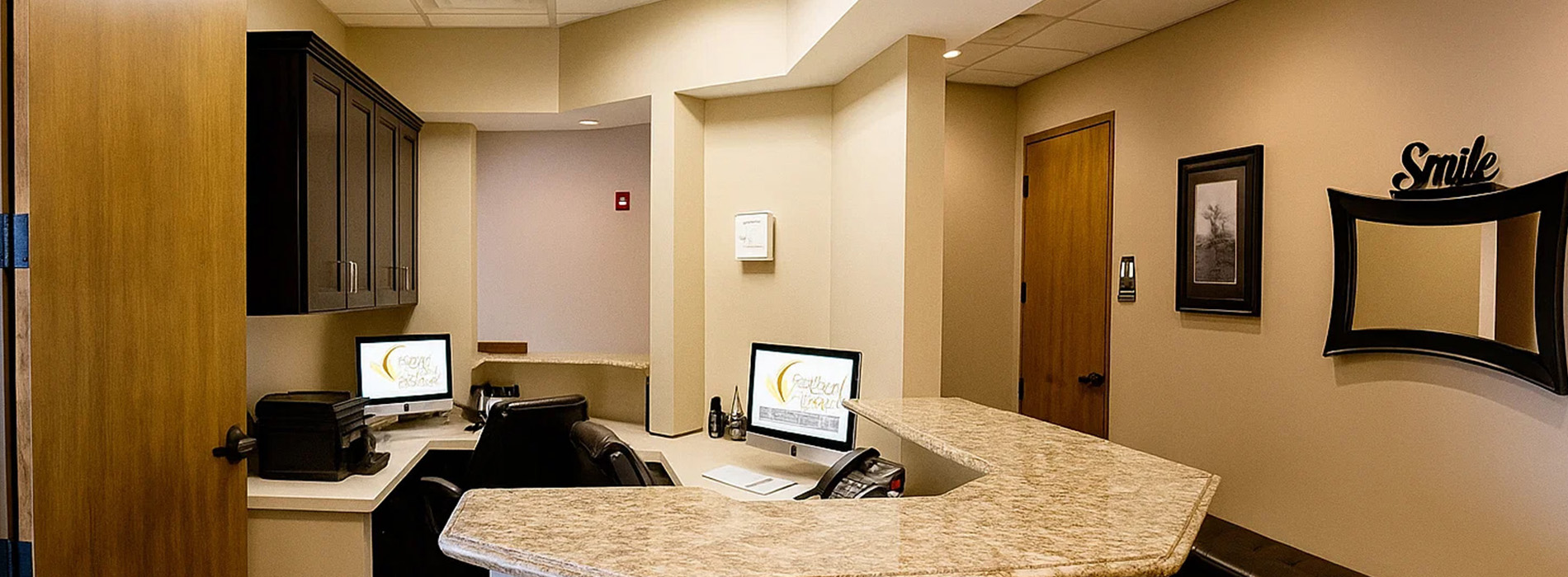 The image depicts an interior view of an office space with a desk area and a computer monitor visible.