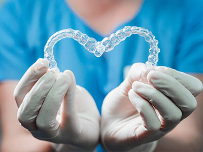 A hand holding a heart-shaped piece of dental equipment.