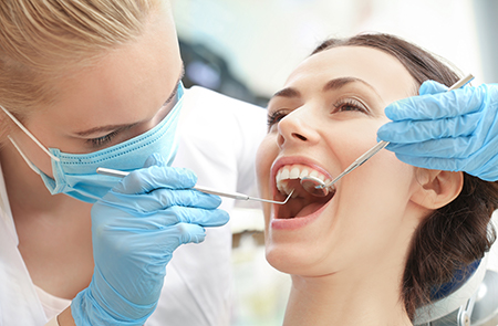 A dental hygienist is performing oral care on a patient with teeth cleaning tools.