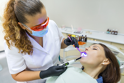 A dental hygienist performing oral care on a patient at a dental office.